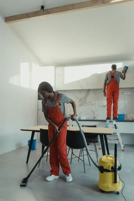 hero-01 A uniformed cleaner holding a basin with cleaning supplies indoors. Ideal for cleaning and sanitation themes.